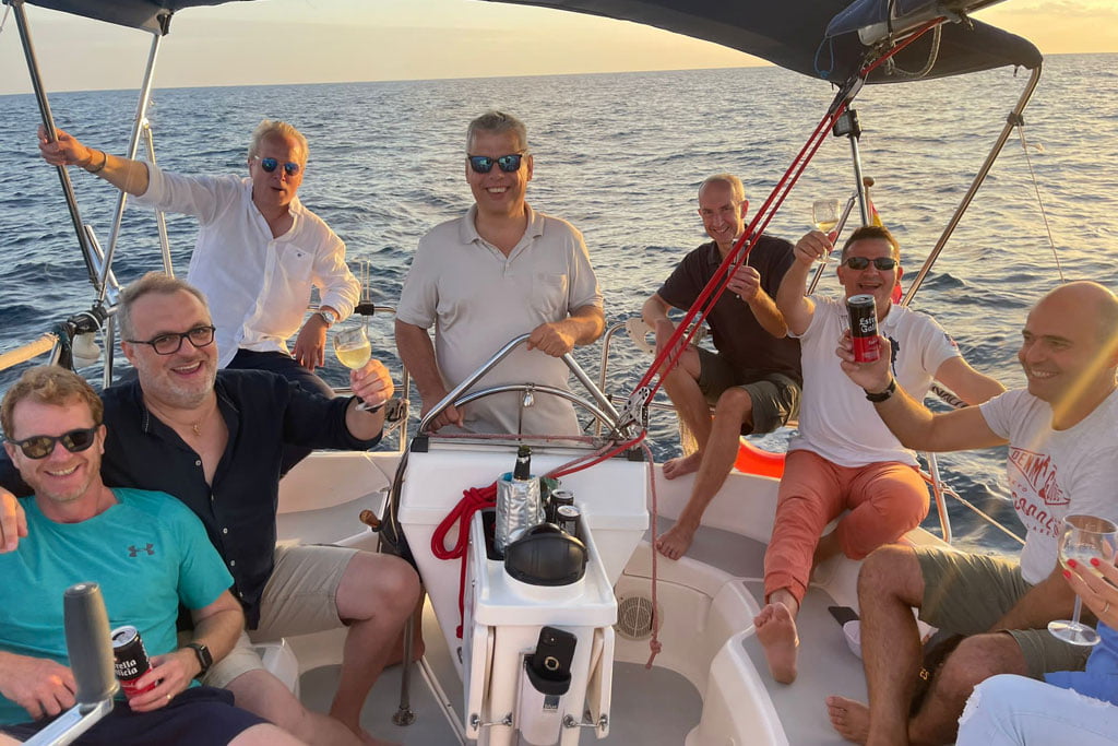 Grupo de amigos brindando en un velero al atardecer en Sitges